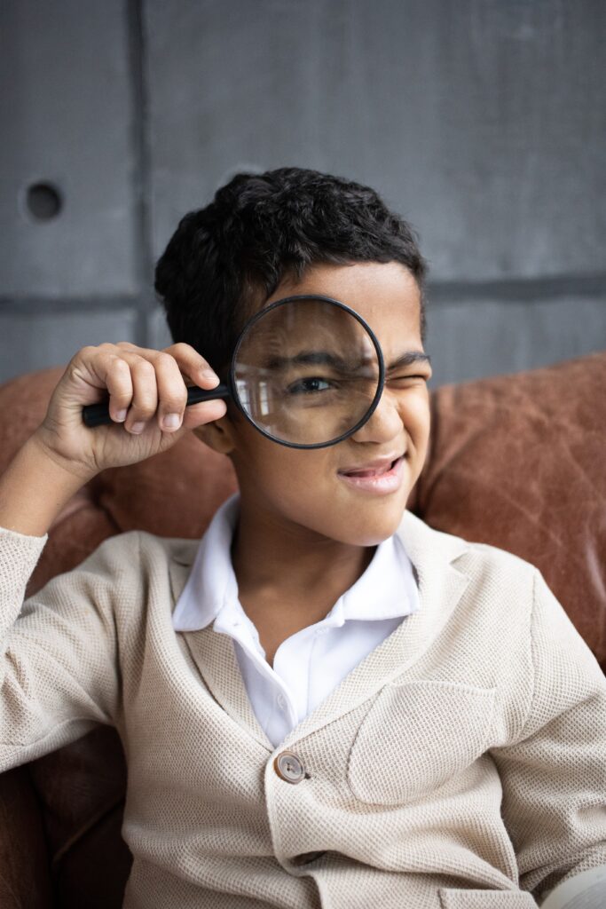 a curious boy holding a magnifying glass to his eye